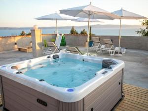 a hot tub on a deck with chairs and umbrellas at Apartment Ela with private jacuzzi in Podgora