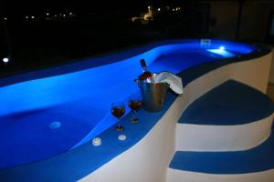 a table with two glasses of wine next to a swimming pool at Honeymoon Beach Studios in Perivolos
