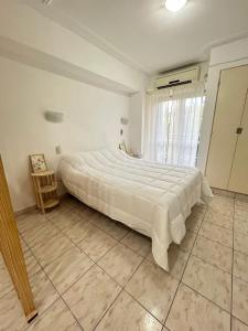 een groot bed in een witte slaapkamer met een raam bij Monoambiente amoblado in San Miguel de Tucumán