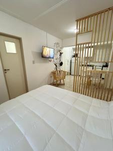 een slaapkamer met een groot wit bed en een televisie bij Monoambiente amoblado in San Miguel de Tucumán