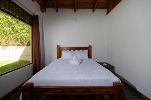 - un ours en peluche assis sur un lit dans une chambre dans l'établissement HeCo House, à Monteverde Costa Rica