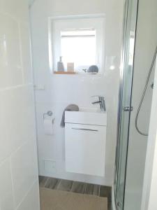 ein weißes Bad mit einem Waschbecken und einem Fenster in der Unterkunft Ein bisschen Luxusfeeling direkt am Neusiedler See in Rust
