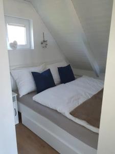 ein weißes Bett mit blauen Kissen in einem Zimmer in der Unterkunft Ein bisschen Luxusfeeling direkt am Neusiedler See in Rust