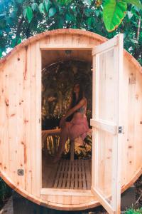 a woman is sitting in a wooden dog house at Como River Retreat in Cavinti