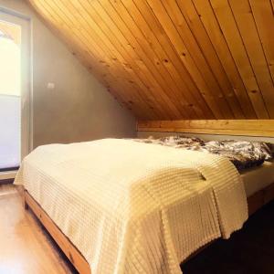 een bed in een kamer met een houten plafond bij Domek na Modyni in Łącko