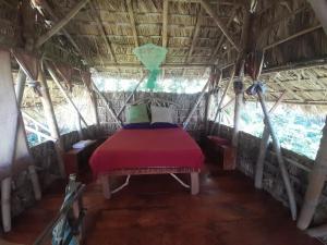 a bed in a room in a hut at El Bamboo Cabins in Balgue