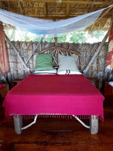 Una cama con una manta rosa encima. en El Bamboo Cabins en Balgue