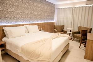 een slaapkamer met een groot bed en twee stoelen bij Confort Fronteira Hotel in Santana do Livramento +58 foto's