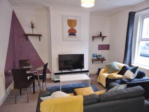 a living room with a couch and a tv at Whitby Elegance in Tynemouth