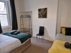 a bedroom with a bed and a chair next to a window at Whitby Elegance in Tynemouth