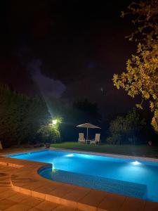 a swimming pool at night with a table and an umbrella at Posada “LA MARGARITA” in San Rafael