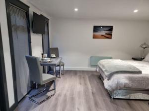 a bedroom with a desk and a bed and a table and chair at Breda Lodge Cosy Studio Space in Belfast