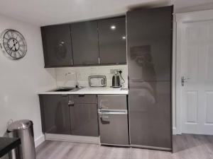a kitchen with a stainless steel refrigerator and a clock at Breda Lodge Cosy Studio Space in Belfast