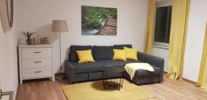 ein Wohnzimmer mit einem grauen Sofa und gelben Kissen in der Unterkunft Top Appartement für Business-Wohnen-Urlaub in Wiener Neustadt