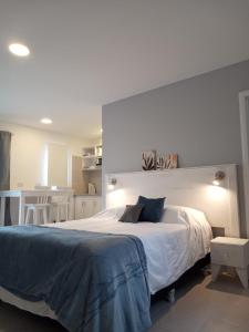 1 dormitorio con 1 cama blanca grande y cocina en Cabañas Aluen en El Calafate