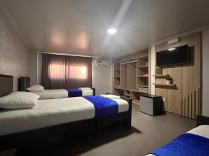 a hotel room with three beds and a flat screen tv at Hotel Cataleya Al-Hoceima in Al Hoceïma