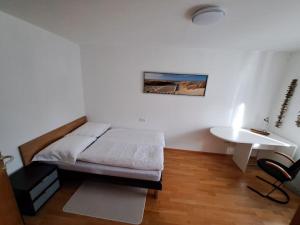 Geräumige Wohnung im Zentrum von Bludenz في بلودينز: غرفة نوم بسرير ومكتب وطاولة