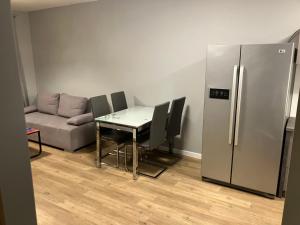 a living room with a table and a refrigerator at Jab Apartment NOWE FORTY Business & Family in Szczecin