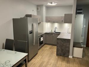 a kitchen with a stainless steel refrigerator and a table at Jab Apartment NOWE FORTY Business & Family in Szczecin
