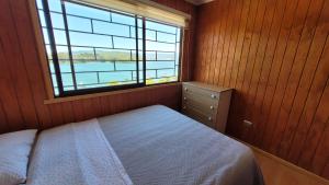 1 dormitorio con cama y ventana grande en Cabañas con hermosa vista al río camino a Niebla, en Niebla