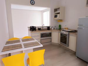 a kitchen with a table and yellow chairs in it at Casa de Maria in Aparecida