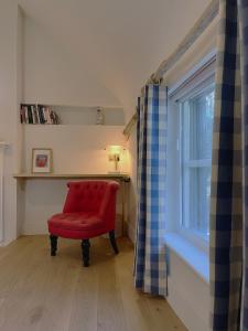 a red chair in a room with a window at Forge Cottage Suffolk in Sudbury