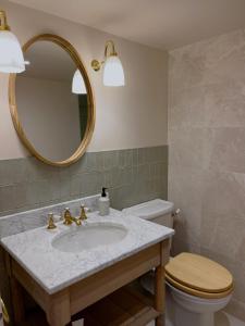 a bathroom with a sink and a toilet and a mirror at Forge Cottage Suffolk in Sudbury