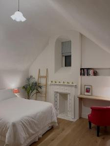 a white bedroom with a bed and a fireplace at Forge Cottage Suffolk in Sudbury