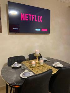 una mesa negra con sillas y un televisor en la pared en Kech Days appartement près de l'aéroport en Marrakech