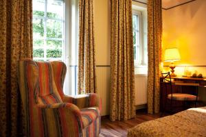 ein Hotelzimmer mit einem Stuhl und einem Fenster in der Unterkunft Landgasthof & Hotel Jagdhof in Stralsund