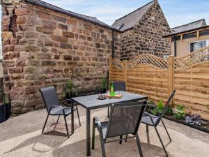 un patio con mesa, sillas y una valla en Chatsworth Cottage en Harrogate