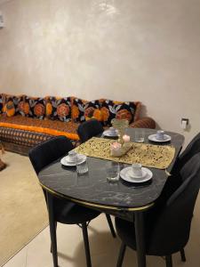 馬拉喀什的住宿－Kech Days appartement près de l'aéroport，客厅配有一张带椅子的黑色桌子和一张沙发。