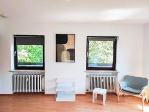 een woonkamer met 2 ramen en een blauwe stoel bij Apartment bei Wasserburg am Inn in Soyen