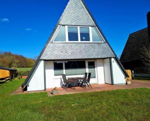 a house with a triangular roof with a table and chairs at Schlei-Perle in Kappeln +4 photos