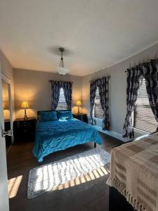 1 Schlafzimmer mit einem blauen Bett und 2 Fenstern in der Unterkunft Spacious and Cozy- near T-station-Quiet Neighborhood! in Malden