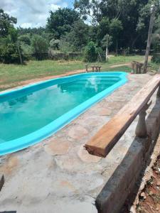 een zwembad met een houten bank ernaast bij Pousada Paraíso Pedacinho Do Céu 2 in Águas de Lindóia