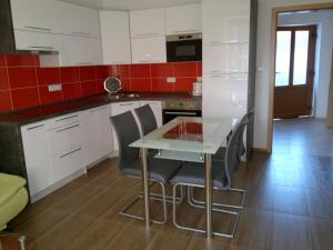 eine Küche mit weißen Schränken, einem Tisch und Stühlen in der Unterkunft Apartmány Adéla in Český Rudolec + 9 Fotos