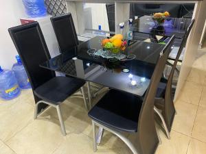 einen Esstisch mit Stühlen und eine Obstschale darauf in der Unterkunft The Residence Golden Tulip 2 Bedroom Apartment, Amuwo Lagos, Nigeria in Lagos