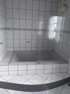 La salle de bains est pourvue de carrelage blanc et d'une baignoire. dans l'établissement Sitio Recanto dos Anjos ES, à Guarapari