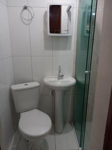 uma casa de banho com um WC, um lavatório e um espelho. em Hospedagem e kitnetes D' Itália em Curitiba
