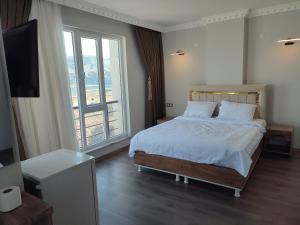 a bedroom with a bed with white sheets and a television at Hasankeyf Hasbahçe Otel in Hasankeyif