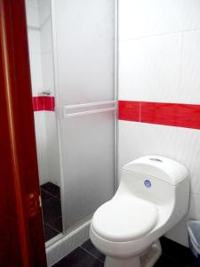 にあるHotel El Cristalの赤いストライプのバスルーム(白いトイレ付)