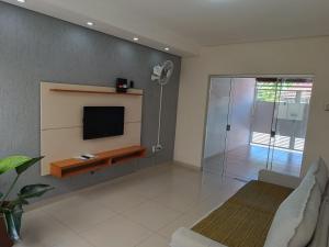 a living room with a tv and a glass shower at Casa de Maria in Aparecida