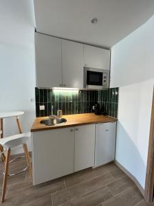 a kitchen with white cabinets and a sink at STUDIO avec PISCINE in Carmaux