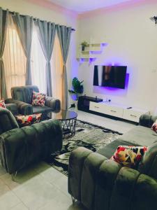 uma sala de estar com sofás e uma televisão de ecrã plano em Kyaliwajala Heights Apartment em Kampala
