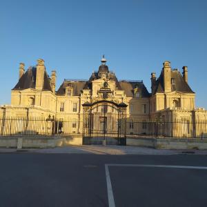 ein großes Gebäude mit einem Tor davor in der Unterkunft B&B avec piscine proche de Paris in Maisons-Laffitte