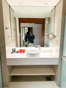 una persona que toma una foto en un espejo de baño en Propriedade privada no Hotel Nacional Rio de Janeiro en Río de Janeiro