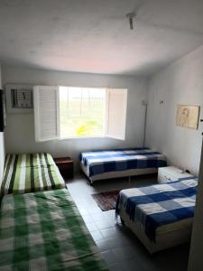 a room with two beds and a window in it at Chalé Barra Sirinhaém in Sirinhaém