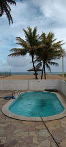 a small swimming pool next to a beach with palm trees at Chalé Barra Sirinhaém in Sirinhaém