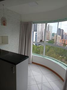 une cuisine avec une grande fenêtre offrant une vue sur la ville dans l'établissement APARTAMENTO SOLAR DA PRAÇA, Aconchegante e Climatizado, à Torres